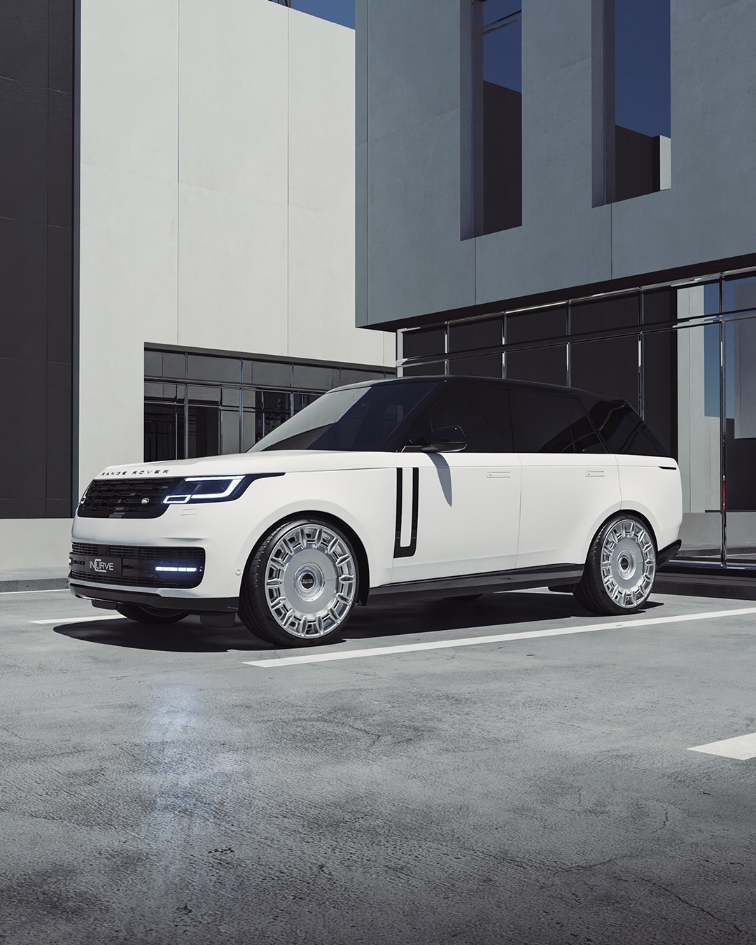 White Range Rover Vogue with a black contrast roof on polished silver Incurve forged wheels outside a modern building